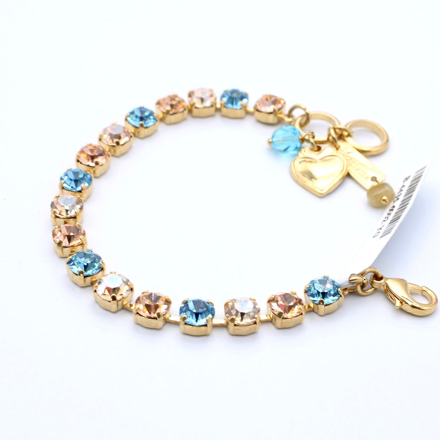 Gold bracelet with blue gemstones and a heart key charm on a white background