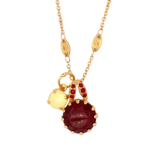 Gold necklace with a red gemstone pendant on a white background
