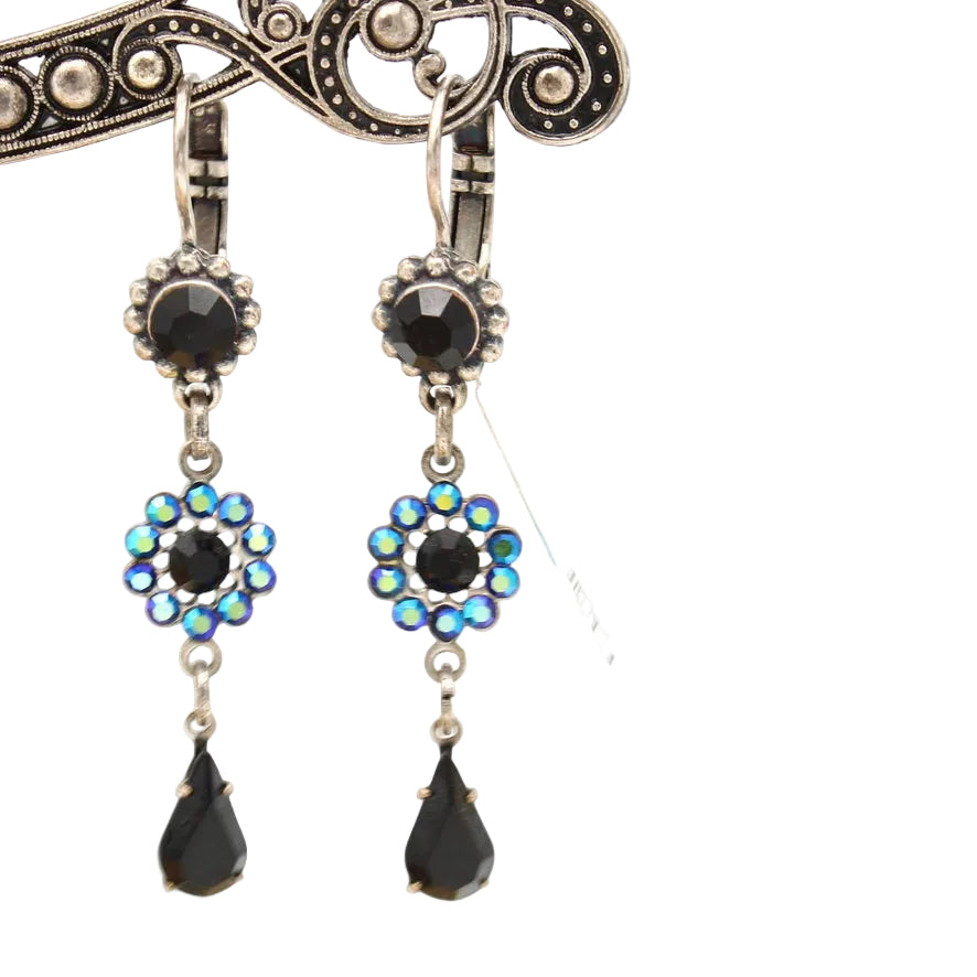 A pair of gothic drop earrings with black faceted stones, iridescent blue and green rhinestone floral clusters, and teardrop-shaped black drops, shown against a white background.