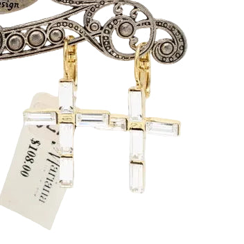 A pair of gold-toned cross-shaped earrings with clear stones, displayed on an ornate silver stand engraved with the name 'Mariana'.