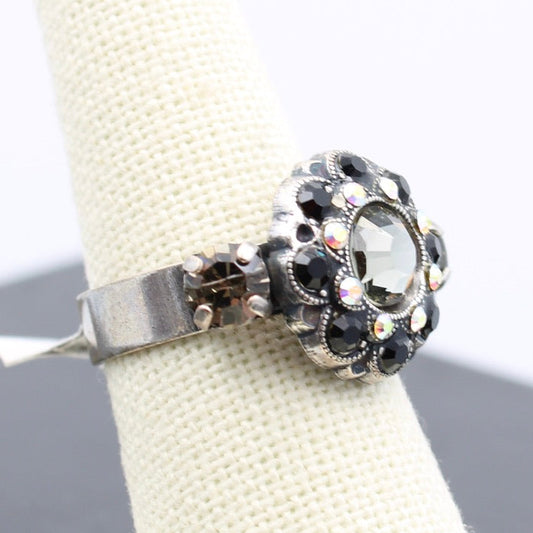 Silver ring with black gemstones on a white cushion