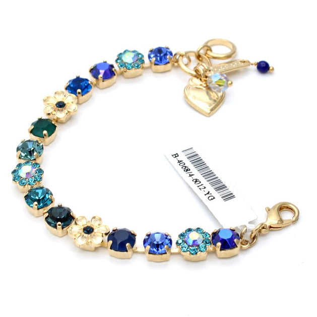 Gold bracelet with blue gemstones and charms on a white background