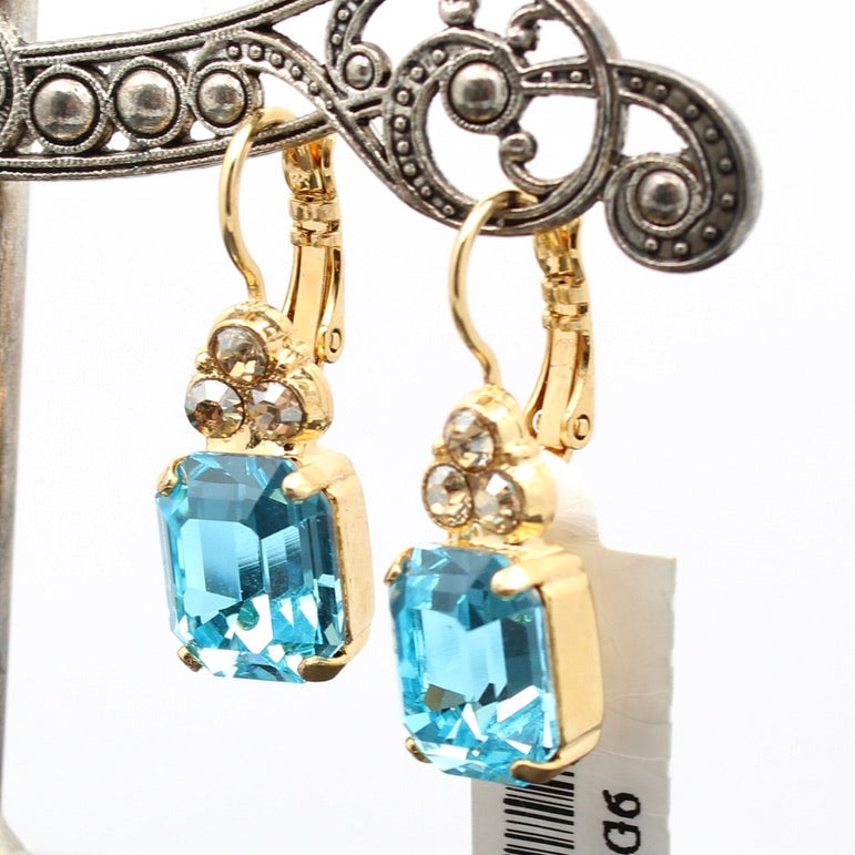 Gold earrings with blue gemstones on a white background