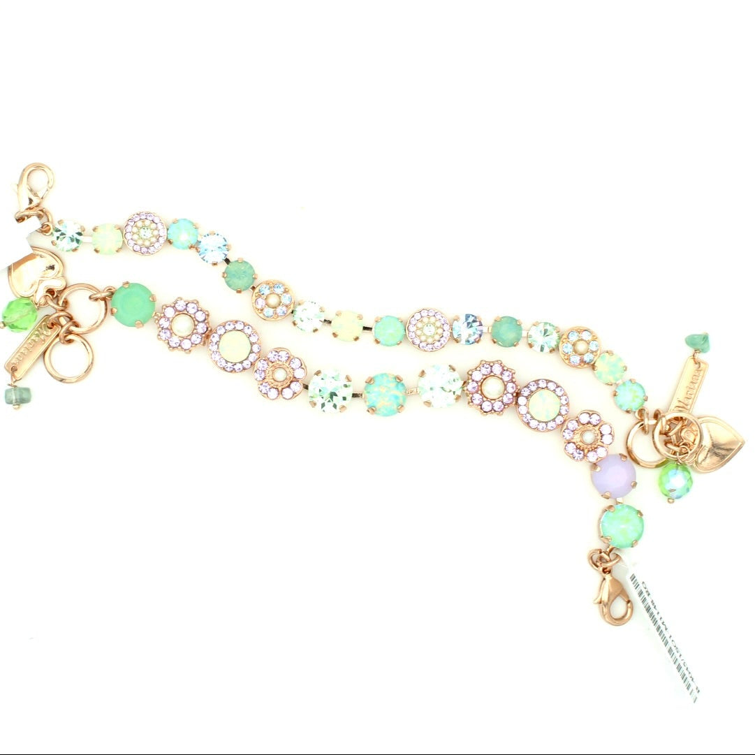 Delicate bracelet with floral charms and green beads on a white background