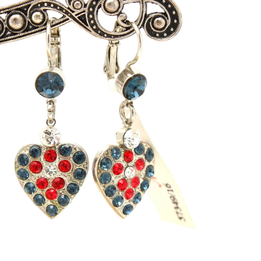 A pair of dangling heart-shaped earrings with blue and red rhinestones, hanging from a decorative metal display stand against a white background.