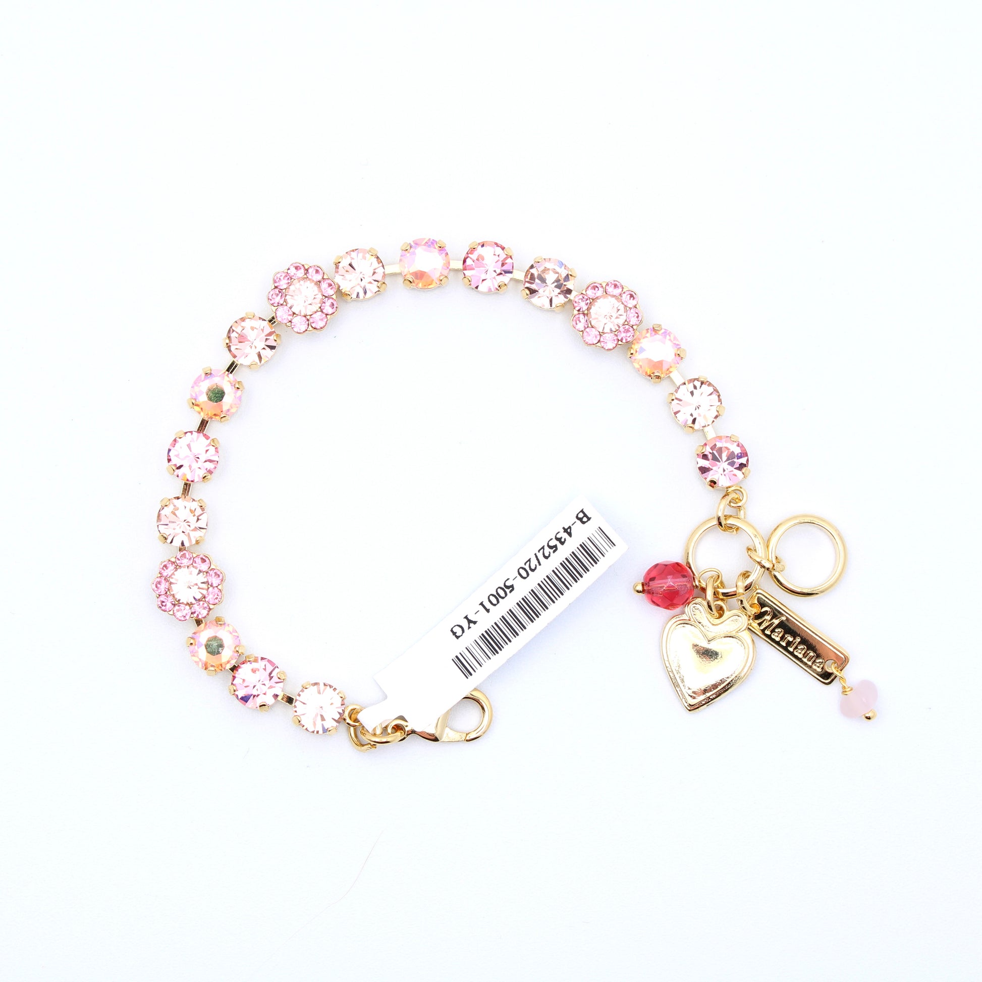 A gold-tone charm bracelet featuring pink and clear rhinestone flower charms, a gold heart-shaped lock charm, a pink bead, and a key-shaped charm engraved with 'Mia', shown on a white background with a product tag attached.