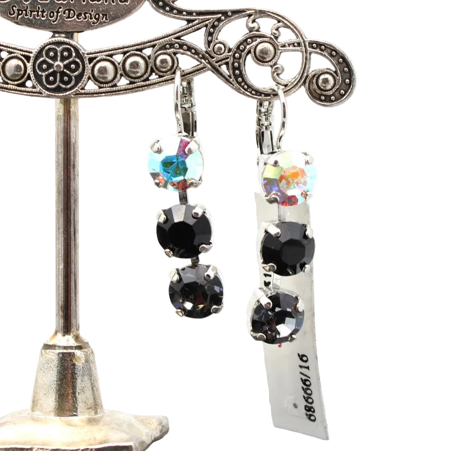 Black and multicolored gemstone earrings on a decorative stand with a white background